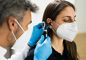 otolaryngologist using a scope to inspect a patient's ear