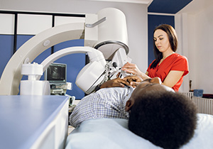 a patient lies on an exam table while a medical professional performs an outpatient procedure