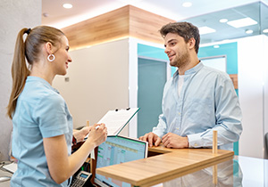 a patient speaks to a nurse at a registration desk